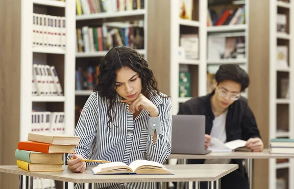 Chica brasileña haciendo investigación sentado en el escritorio en la biblioteca — Foto de Stock