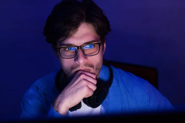 Desarrollador reflexivo mirando la pantalla de la computadora que trabaja desde casa, con poca luz —  Fotos de Stock