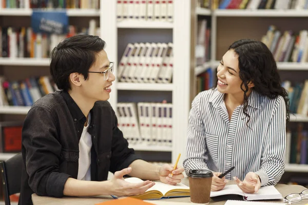 Couple multiculturel partageant des idées dans une bibliothèque moderne — Photo