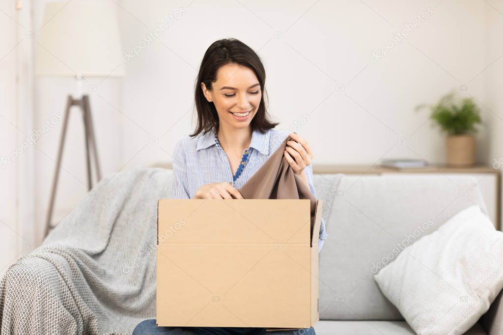 Smiling girl putting clothes in cardboard box
