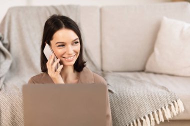 Woman talking on cellphone sitting on the floor