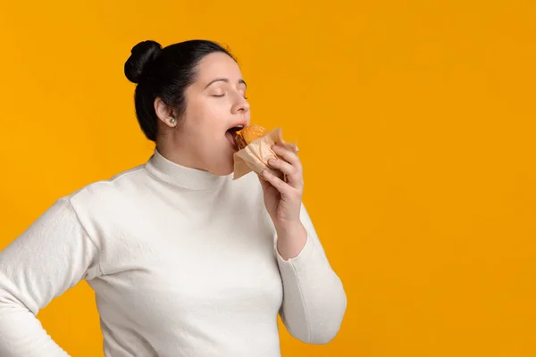 Young Plump Woman Eating Tasty Hamburger With Closed Eyes — Stok fotoğraf