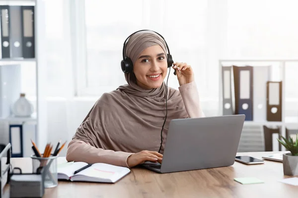 Beautiful muslim female manager wearing headset having online conference with partners — ストック写真
