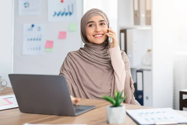 Joyful Muslim Woman Having Call While Working On Laptop In Office — Stockfoto