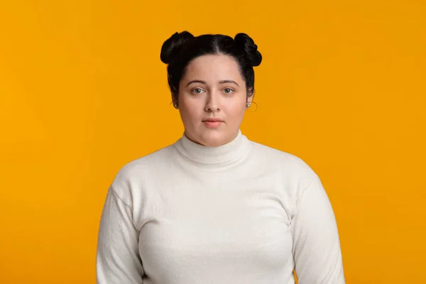 Young plus size girl with double bun hairstyle over yellow background — Stock fotografie