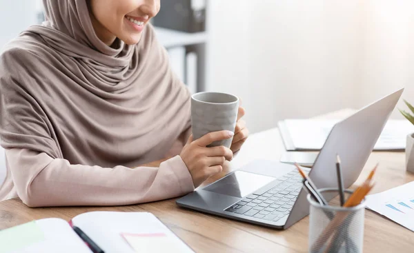 Muslim Woman Drinking Coffee At Desk And Working On Laptop — ストック写真