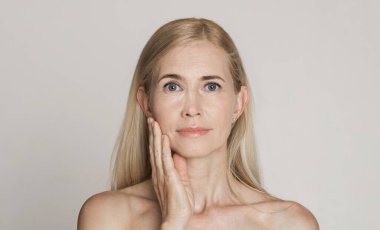 Beautiful caucasian middle-aged woman touching her face