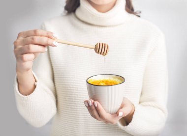 Woman drinking Cup of ayurvedic golden turmeric latte