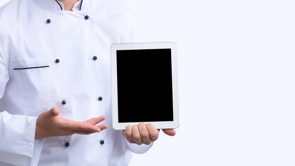 Chef irreconocible mostrando pantalla de tableta vacía sobre fondo blanco, recortado — Foto de Stock