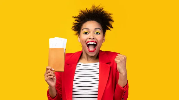 Emocionada mujer negra sosteniendo boletos y pasaporte en el estudio —  Fotos de Stock