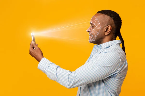 Mature african man scanning his face with mobile app — ストック写真