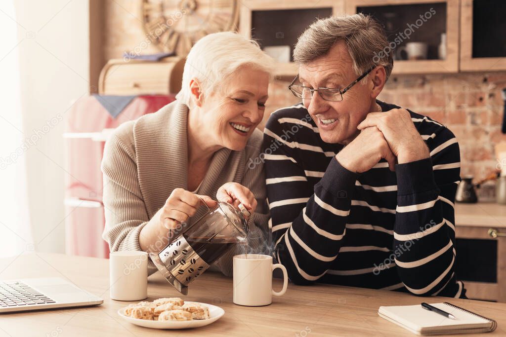 Romantic elderly couple enjoying morning coffee in kitchen together