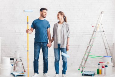 Couple with paint and instruments planning home repair