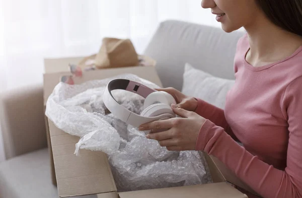 Girl in living room unpacking cardboard box parcel — Stockfoto