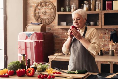 Smiling Senior Woman Relaxing With Cup Of Coffee In Kitchen