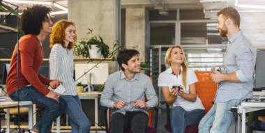 Friendly young business team chatting during coffee break