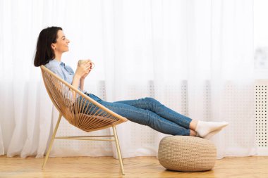 Happy girl drinking coffee sitting in chair