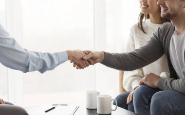 Couple And Psychologist Shaking Hands After Therapy In Office, Cropped