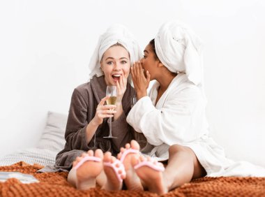 Gorgeous girlfriends sharing secrets, drinking champagne while having pedicure