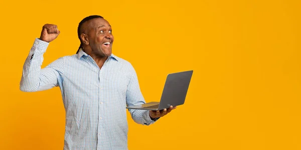 Excited african middle aged man with laptop cheering his win — Stockfoto