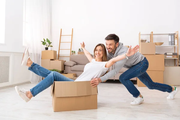Smiling young couple having fun and riding in boxes — Stock Photo, Image