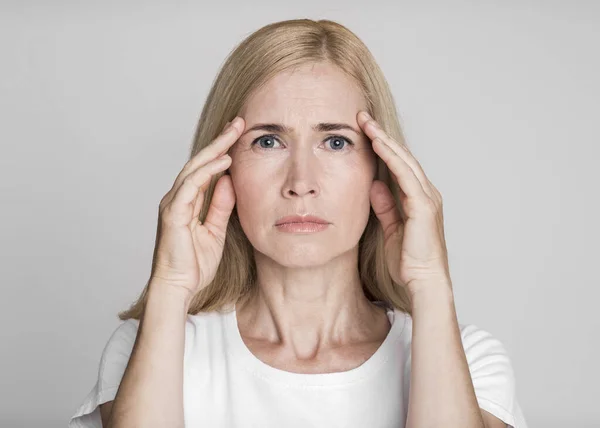 Triste mujer de mediana edad sufre de fuerte dolor de cabeza — Foto de Stock