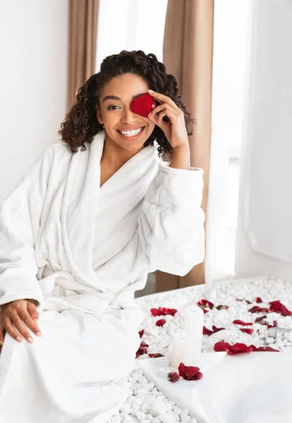 Joyeuse fille noire plaçant pétale de rose sur son oeil — Photo