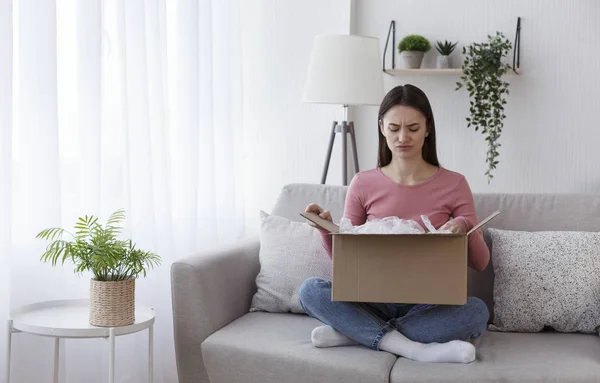 Young girl unpacking box and feeling frustrated — Stockfoto