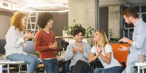 Young creative team cheering new comer girl in office — Stockfoto