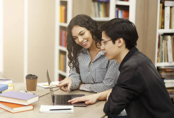 Sonriente pareja multicultural estudiando en la biblioteca moderna — Foto de Stock