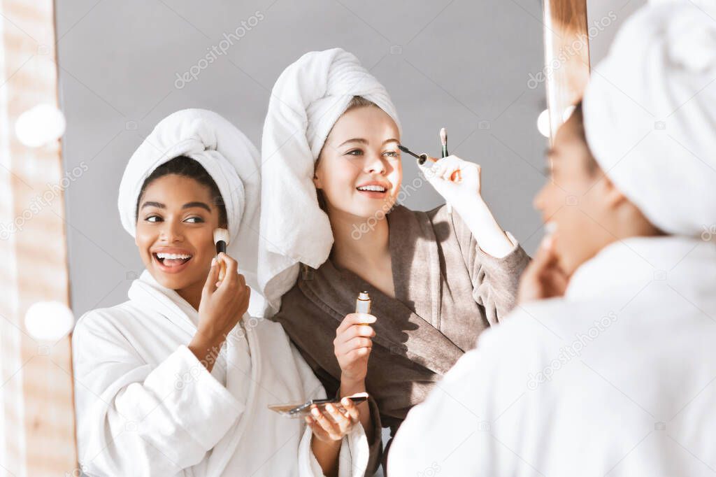 Girlfriends in bathrobes getting ready for party, putting make up