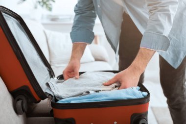 Preparing for trip. Guy packing clothes into suitcase
