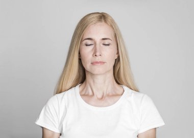 Beautiful middle-aged woman posing with closed eyes