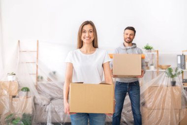 Happy young couple collecting clothes into boxes and planning repair