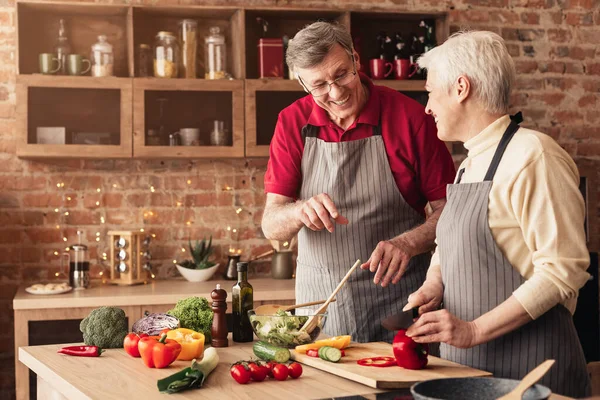 Happy senior couple enjoying preparing dinner together, cooking in kitchen — Stok fotoğraf