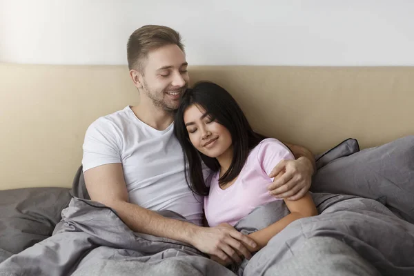 Loving Diverse Couple Hugging Lying In Bed Enjoying Weekend — Stok fotoğraf