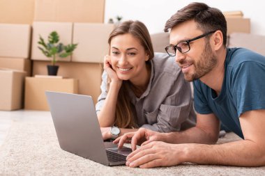 Smiling young loving couple on floor in new flat planning repair