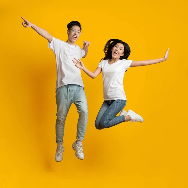 Carefree asian millennial man and woman jumping in air — Zdjęcie stockowe