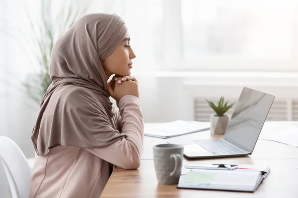 Portrait of thoughtful arabic female entrepreneur sitting at workplace in office — Stockfoto