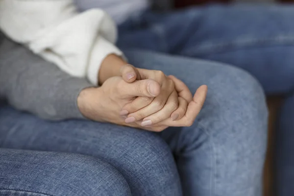 Дружина тримає руки підтримуючи один одного сидячи в приміщенні, обрізаний — стокове фото