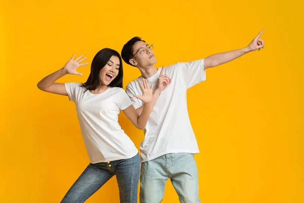 Emotional asian man and woman dancing on yellow background — 스톡 사진