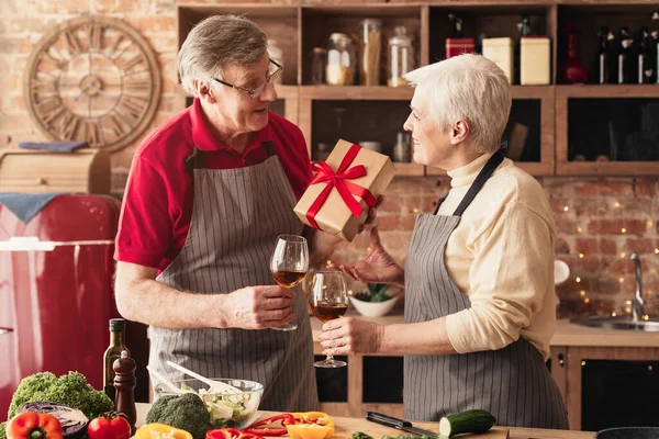 Romantic senior couple exchanging gifts and drinking wine in kitchen — Φωτογραφία Αρχείου