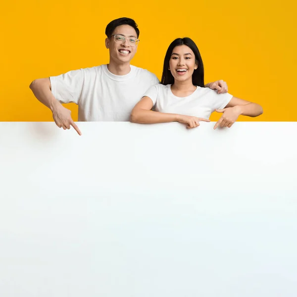 Asian lovers leaning on big blank board for advertisement — Zdjęcie stockowe