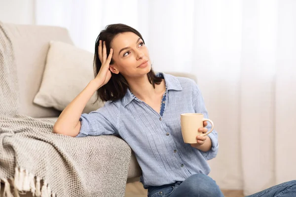 Jovencita alegre sentada en el suelo con una taza de té — Foto de Stock