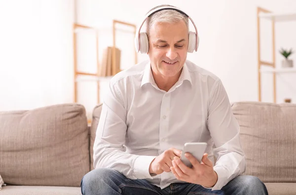 Elderly man listening to music sitting on sofa — Φωτογραφία Αρχείου