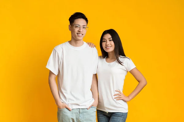 Young asian couple posing on yellow background