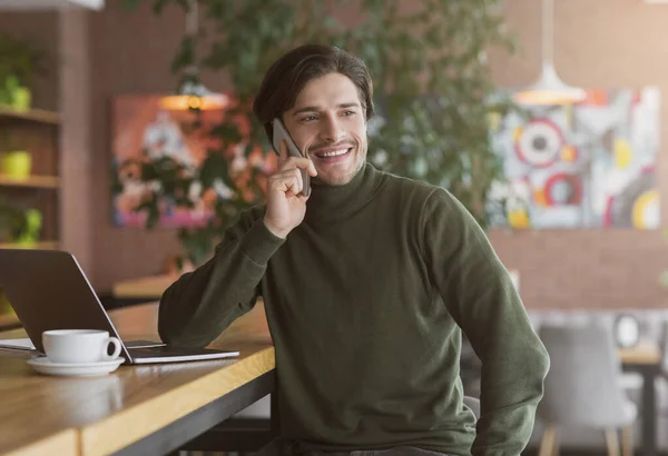 Hombre guapo freelancer hablando por teléfono con los clientes — Foto de Stock