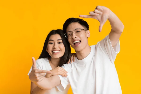 Young asian man and woman show frame sign with hands — Zdjęcie stockowe