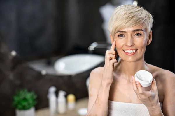 Gorgeous Woman Applying Facial Cream Standing In Bathroom At Home — Stockfoto