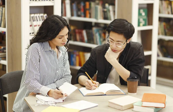 두 명의 집중적 인 다 인종 학생들 이 도서관에서 배우고 있다 — 스톡 사진